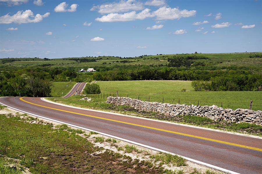 Contact Us - Winding Road Stretching into the Distance in a Landscape of Slightly Rolling Hills, Trees, and Grassy Fields