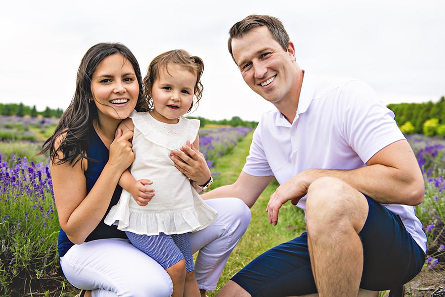 Personal Insurance - Mother, Father, and Toddler Daughter in a Field of Purple Wildflowers, Smiling Together